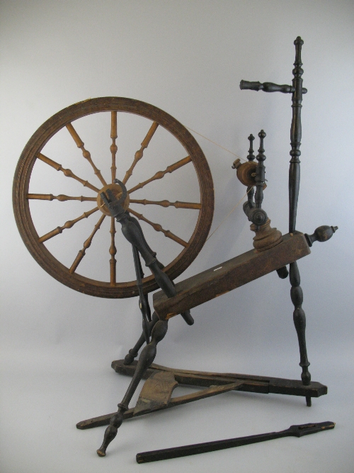 A Scandinavian spinning wheel, the fruit wood and pine frame with ebonised turned supports and