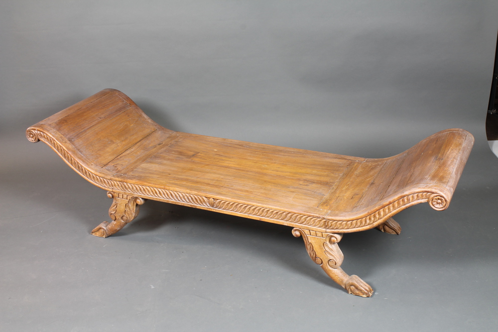 An Eastern carved hardwood day bed in the Regence taste with gadroon carved decoration, raised on
