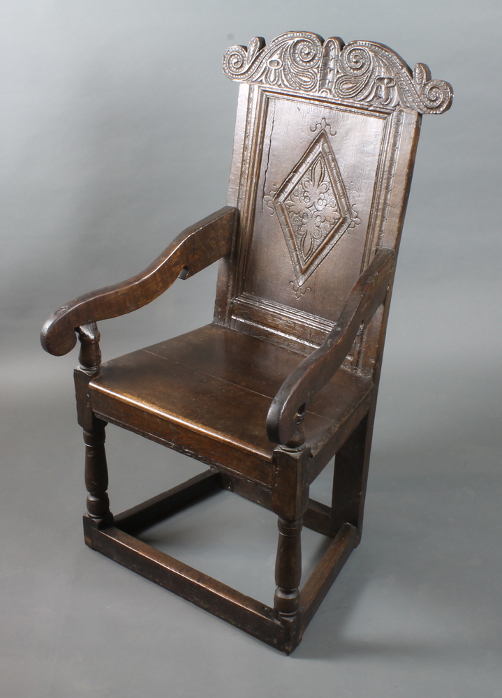 A 17th Century oak Wainscot elbow chair, having foliate and scroll carved cresting rail, the