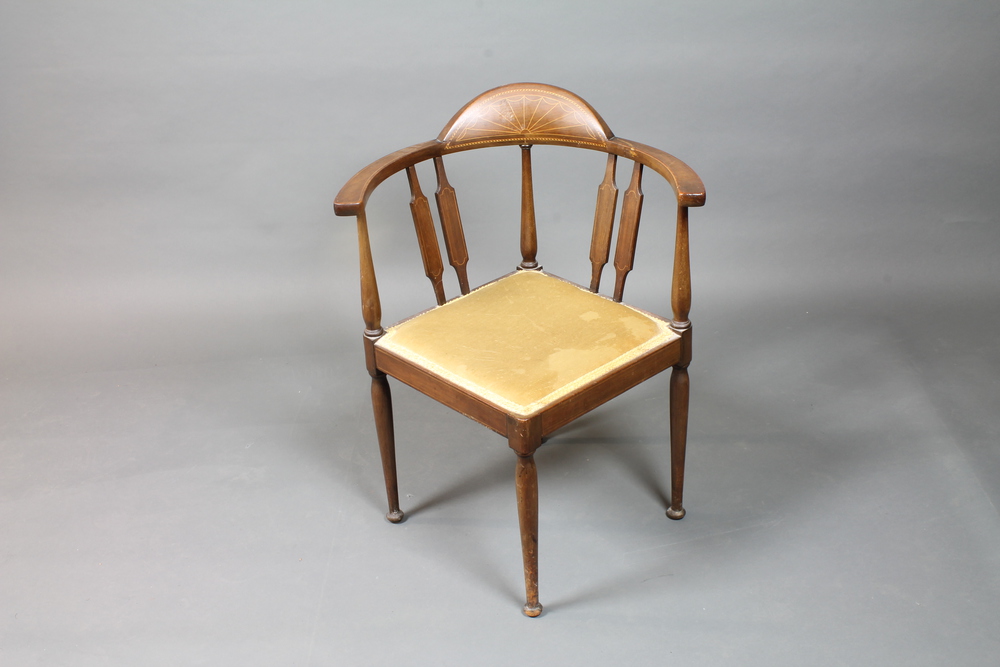 An Edwardian Sheraton revival mahogany corner elbow chair  with patterae cresting rail, raised on