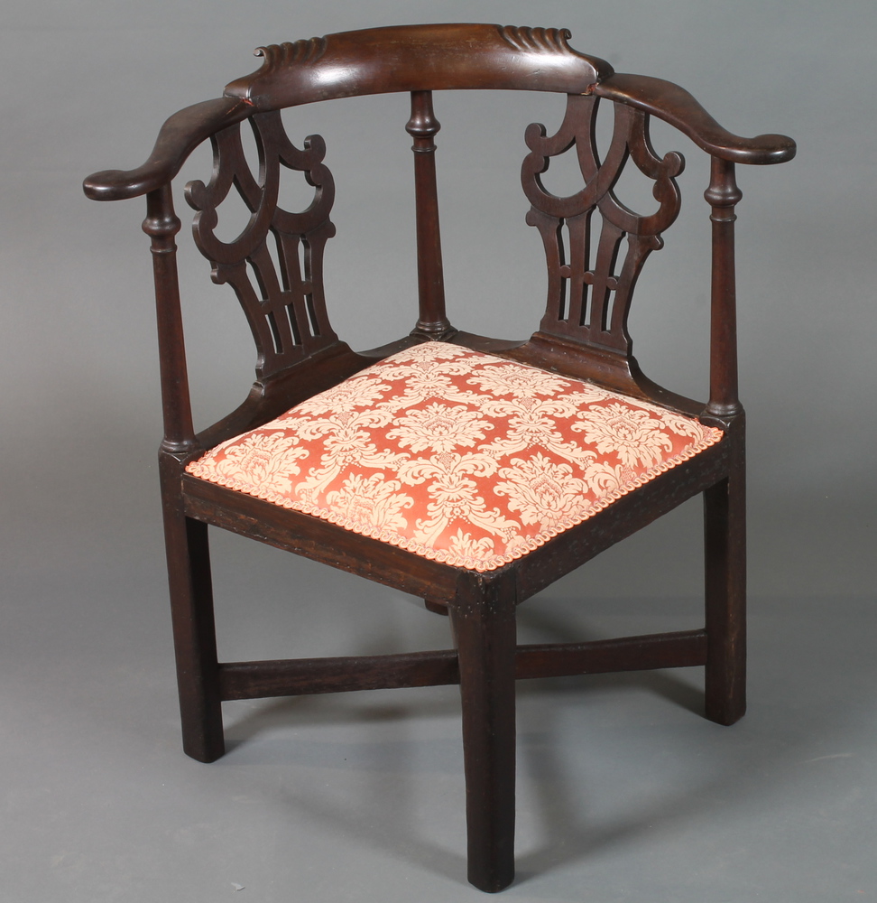 A George III mahogany smoker`s bow corner chair having  scrolled cresting rail, pierced splats,