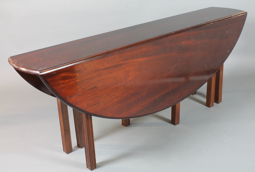 A George III style mahogany Wake table, having an oval drop leaf top with swing out leg support,