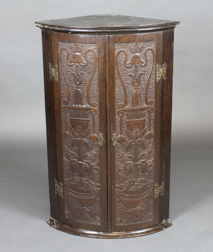 A 19th Century carved oak hanging corner cabinet with shelved interior enclosed by panelled doors