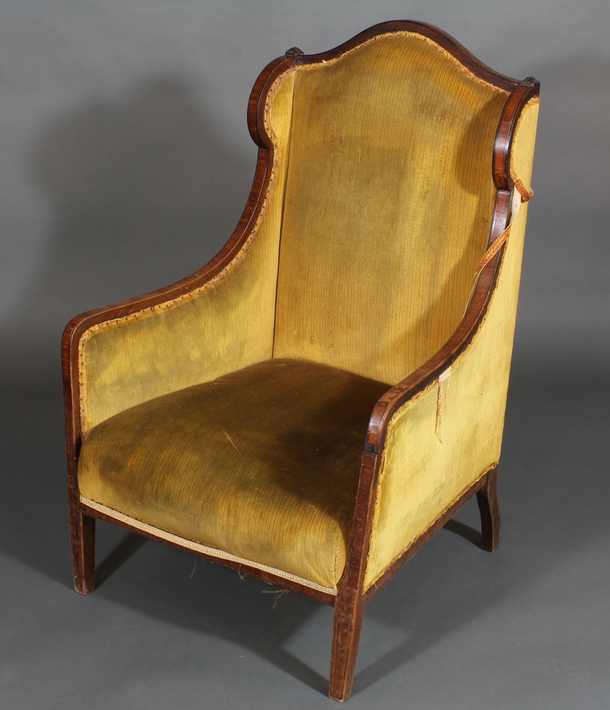 An Edwardian inlaid mahogany winged armchair upholstered in  yellow material, raised on square