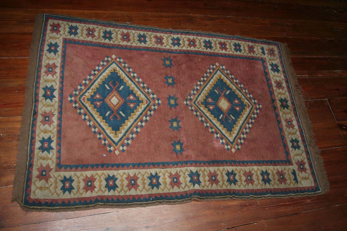 A PERSIAN RUG WITH GEOMETRIC DESIGN ON RED GROUND, 198cm x 133cm.