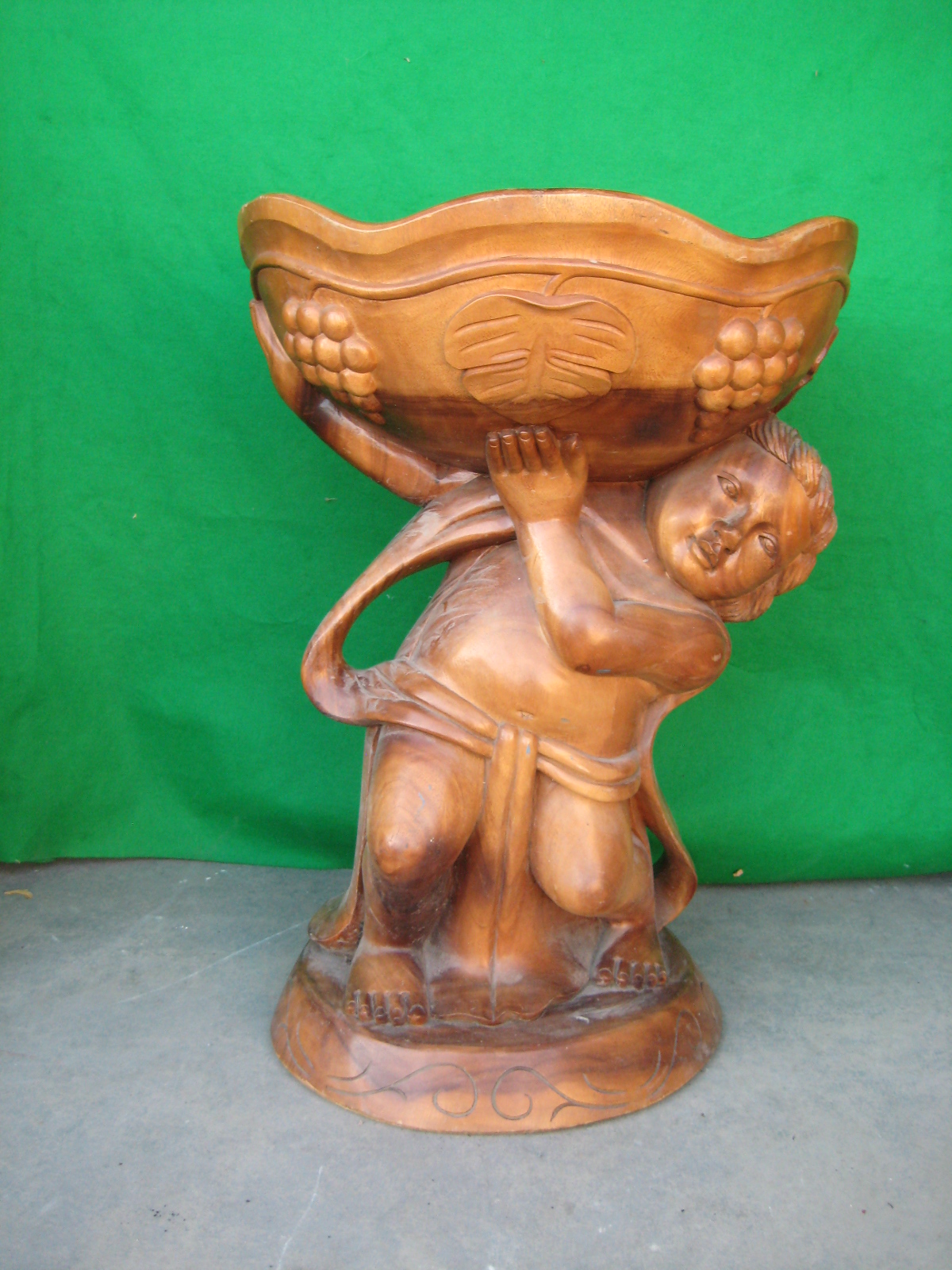 A large hardwood carving of a youth carrying a fruit bowl