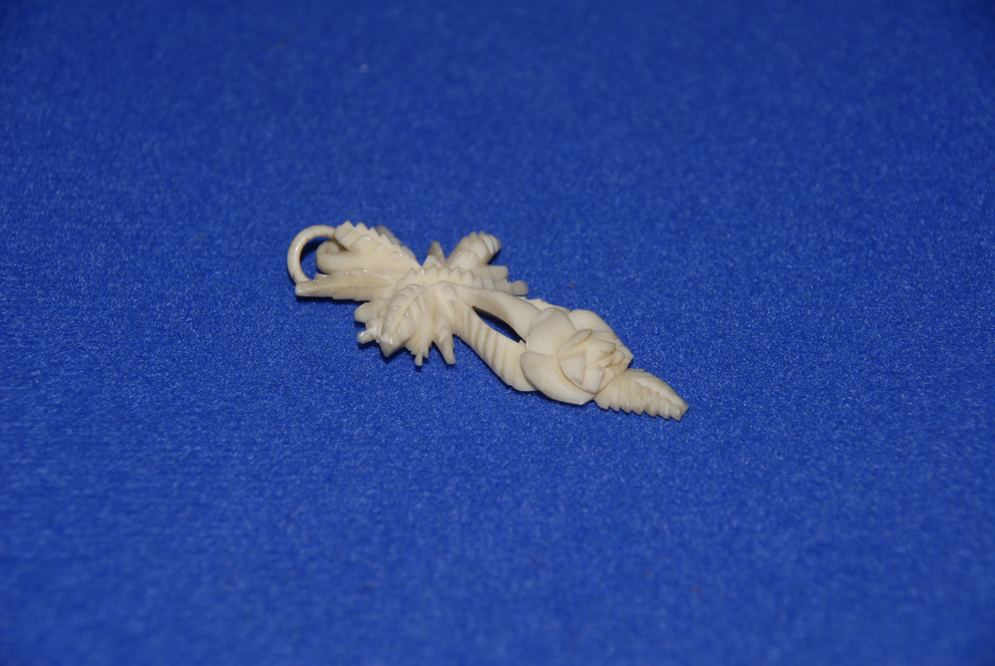 A carved bone floral pendant, as a cross