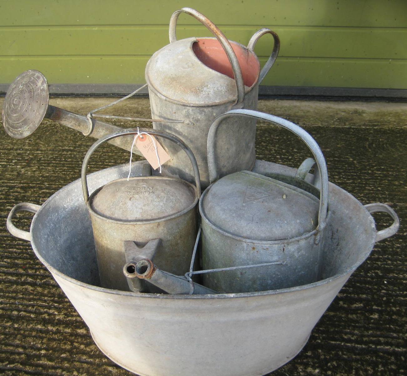 A galvanised bath, and three watering cans