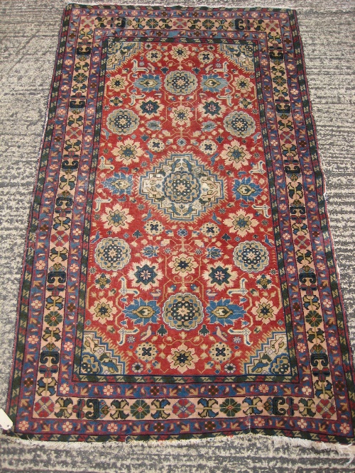 A Middle Eastern tribal rug having central field of flowerheads and birds on a madder ground,