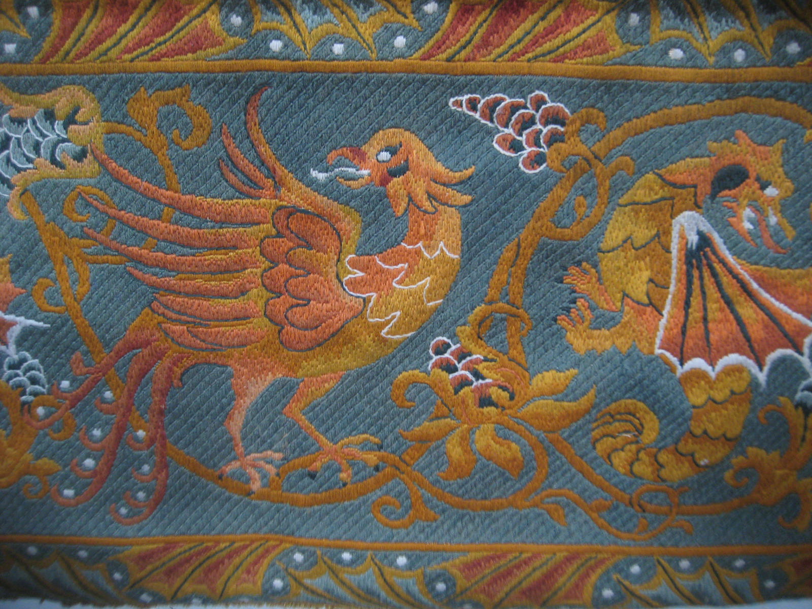 A wall hanging woolwork of two dragons and a griffin