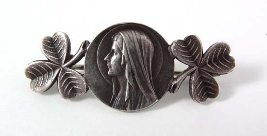 A white metal brooch formed as head of the virgin Mary flanked by 2 shamrock 1 3/4" wide