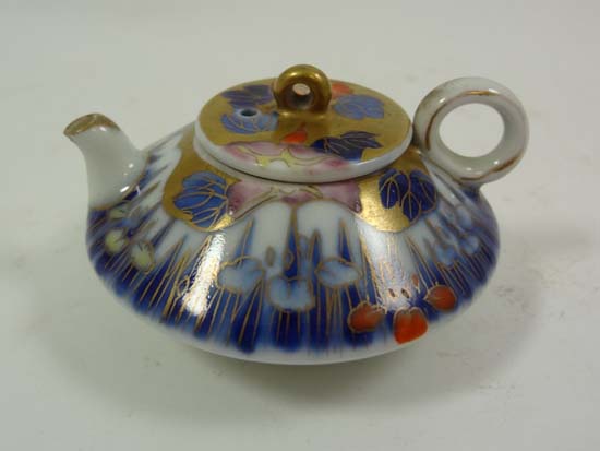 A miniature Japanese teapot decorated in blue, red, pink and yellow floral design with gilding to