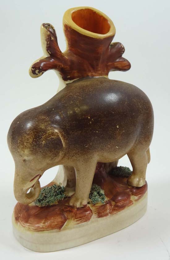 A Victorian Staffordshire spill vase modelled as an elephant before a tree shaped spill vase. Height
