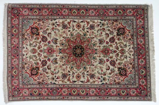 Rug / carpet : a handmade rug with beige ground and pink central design and border, with further