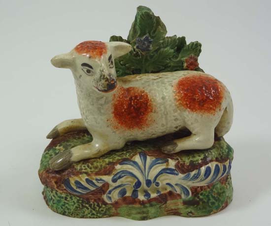 An early 19thC bocage figure of a recumbent sheep on a grassy base with blue detail. Height 4"