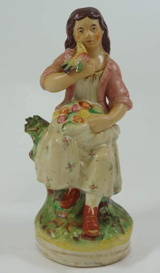 A Victorian Staffordshire romantic rural figure of a seated girl with apron full of flowers and
