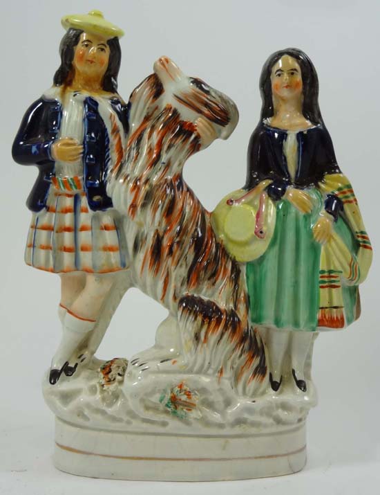 A Victorian Staffordshire figure depicting a couple in Highland dress flanking an oversized goat.