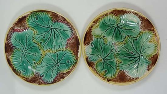 A pair of moulded majolica leaf plates, decorated with 3 green leaves tinged with yellow on a