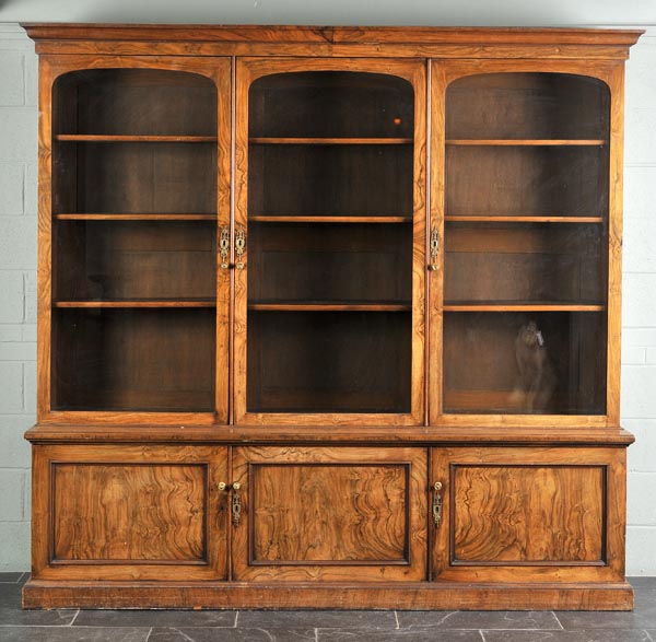 * A Victorian figured walnut veneered bookcase, the ogee cornice over three glazed doors enclosing