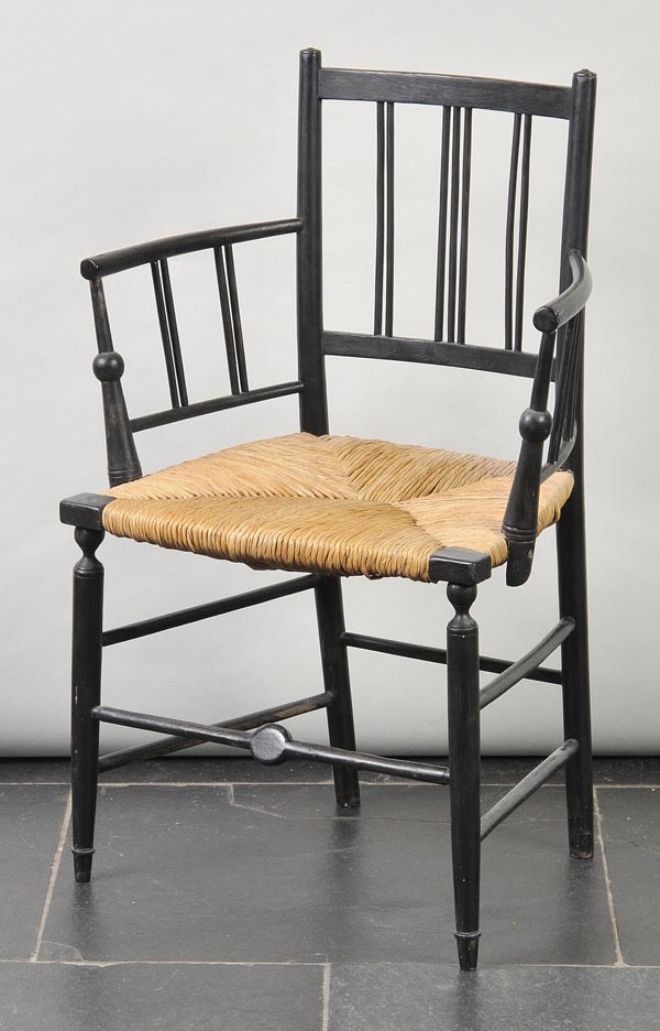 * A William Morris Sussex style chair, ebonised with spindle uprights over arms, rush seat on