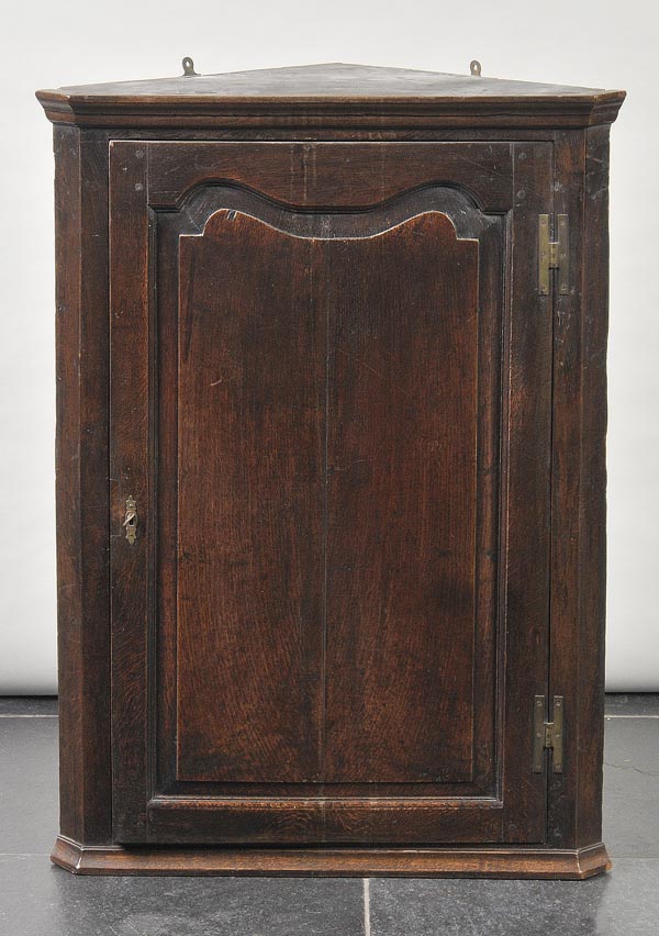 * A 19th-century oak hanging corner cabinet, with single panel door, enclosing shelved interior,