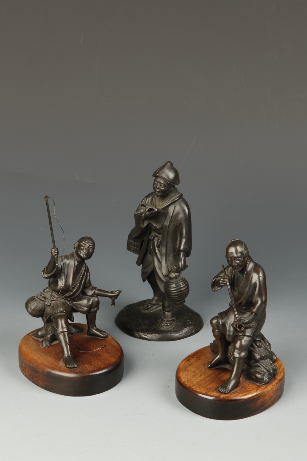 A JAPANESE BRONZE FIGURE OF A NIGHT WATCHMAN, Meiji, 6.5" high; and two further bronze figures of