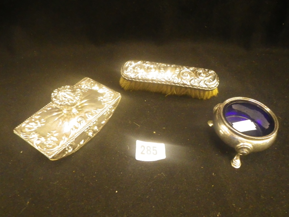 A silver repoussé decorated desk blotter, a silver-backed clothes brush and a silver salt (3)