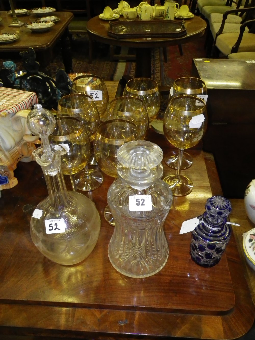 A blue overlaid cut-glass bottle, two decanters and a set of eight gilt banded wine glasses