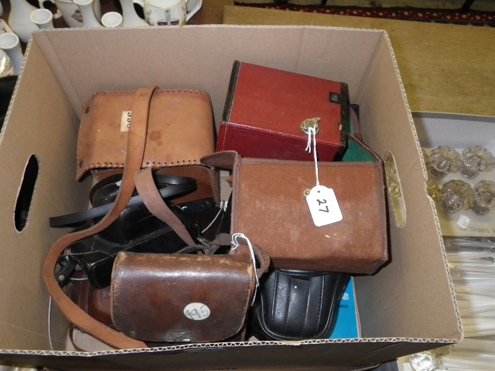 A red box Brownie camera, a Minolta camera, and a collection of others similar