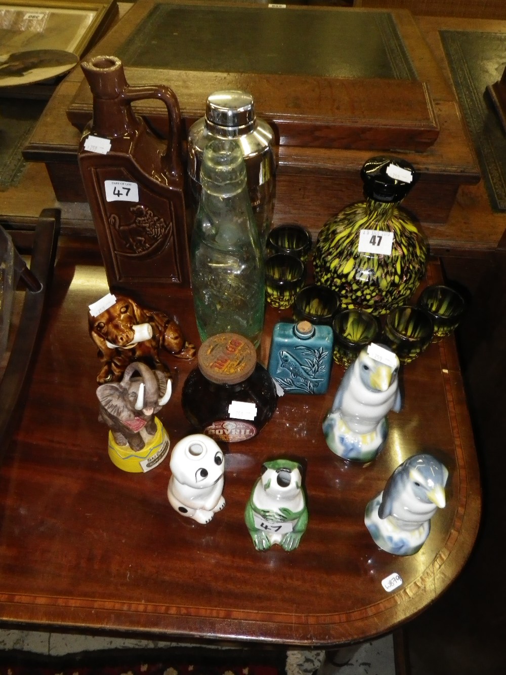 A multi-coloured decanter with glasses, a collection of bottles and similar items