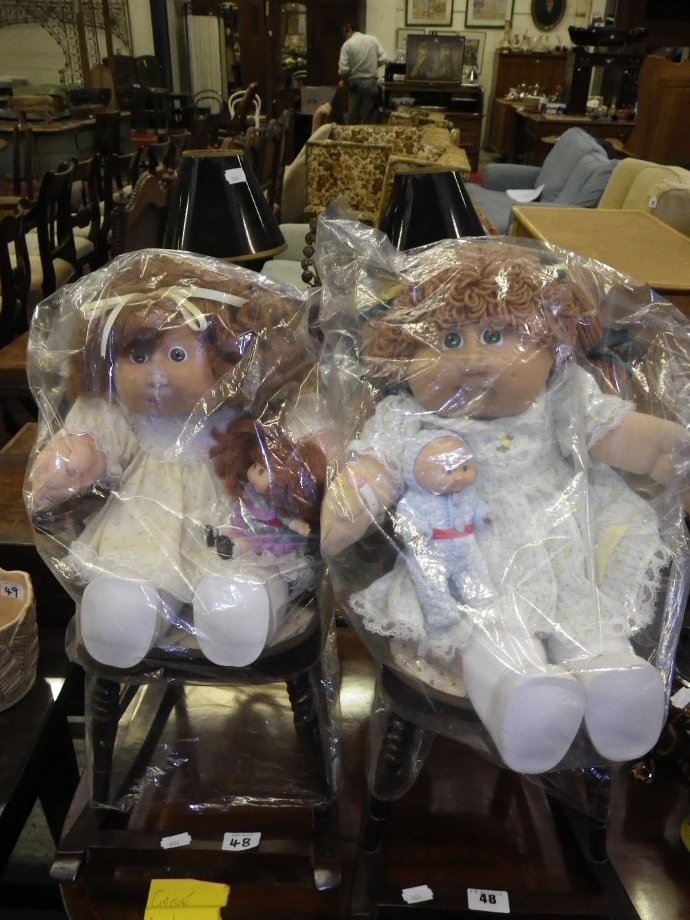 A Vintage Cabbage Patch doll with her baby in a wooden rocking chair and another similar (the ‘