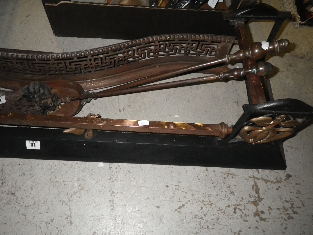 An Edwardian Art Nouveau style iron and brass fender, another fender and two fire tools