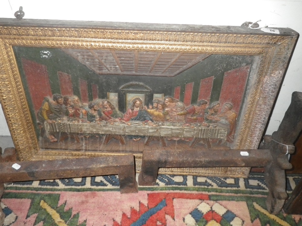 A cast iron plaque depicting `The Last Supper` and a pair of iron fire dogs