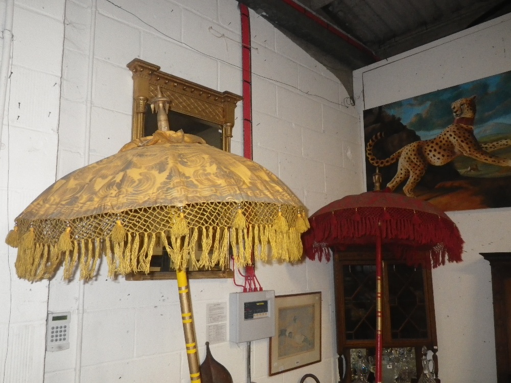 A brightly decorated red parasol with fringing, another similar in yellow and a Venetian mask