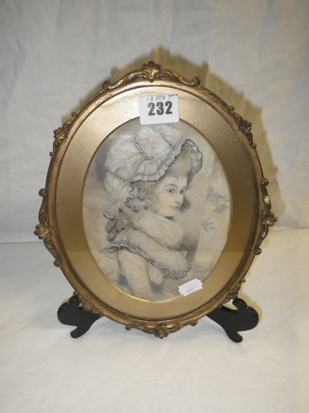 An oval portrait study of a young girl wearing an elaborate bonnet in gilt frame