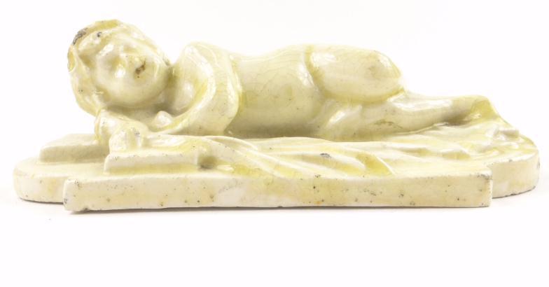 19th Century creamware model of a recumbent young child on plinth base, 14cm in length : For