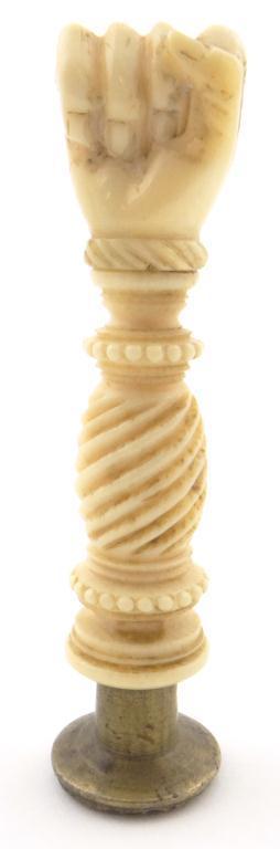 19th Century bone and brass pipe tamper, the handle carved with a clenched fist on a fluted stem,