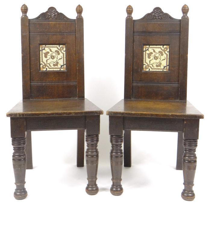 Pair of aesthetic oak hall chairs, each set with a Pugin style Minton mosaic pattern tile to the