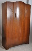 A 1930's Art Deco oak double wardrobe. The shaped door to centre having open storage within complete