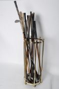 A brass umbrella / stick stand with sixteen assorted golf clubs, some with wooden shafts