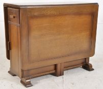 A 1930's Art Deco oak drop leaf harvest dining table. The uprights to centre having cupboard within.