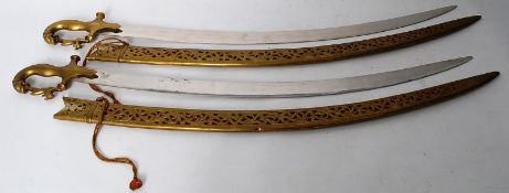 A pair of vintage brass decorative swords with lion and rabbit detail to handle and pierced design