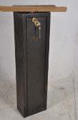 A 20th century wall mountable metal gun cabinet complete with keys having a fall front door
