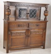 A Jacobean style oak court cupboard. The base with cupboard under short drawers, atop a glazed