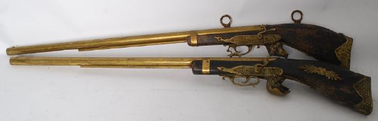 A pair of decorative brass and wood coat hanging guns complete with hooks