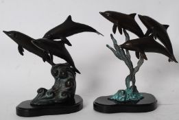 A pair of hollow cast bronze dolphin figures mounted over plinth bases of naturalistic form