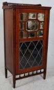 An Edwardian walnut music cabinet. The upright body having glass door with mirror door atop. Shelved