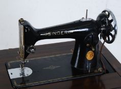 A 1930's Singer sewing machine in a walnut Art Deco case having metamorphic action to the inside