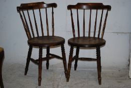A pair of Edwardian 20th century dining chairs, turned legs united by stretchers and being spindle