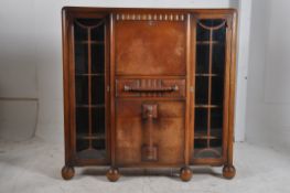 A 1930's Art Deco oak bureau bookcase display cabinet. Raised on bun feet having central bureau over